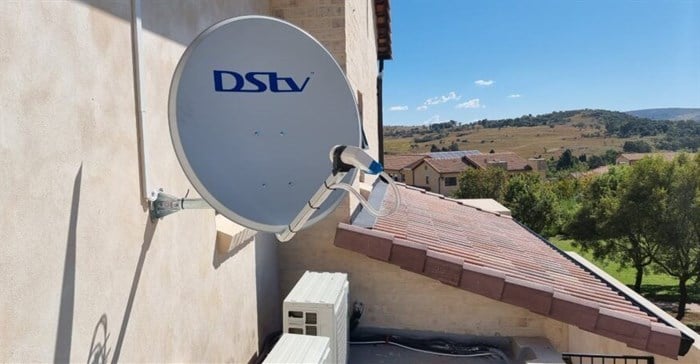 DStv satellite dish wall mounted next to a double storey home