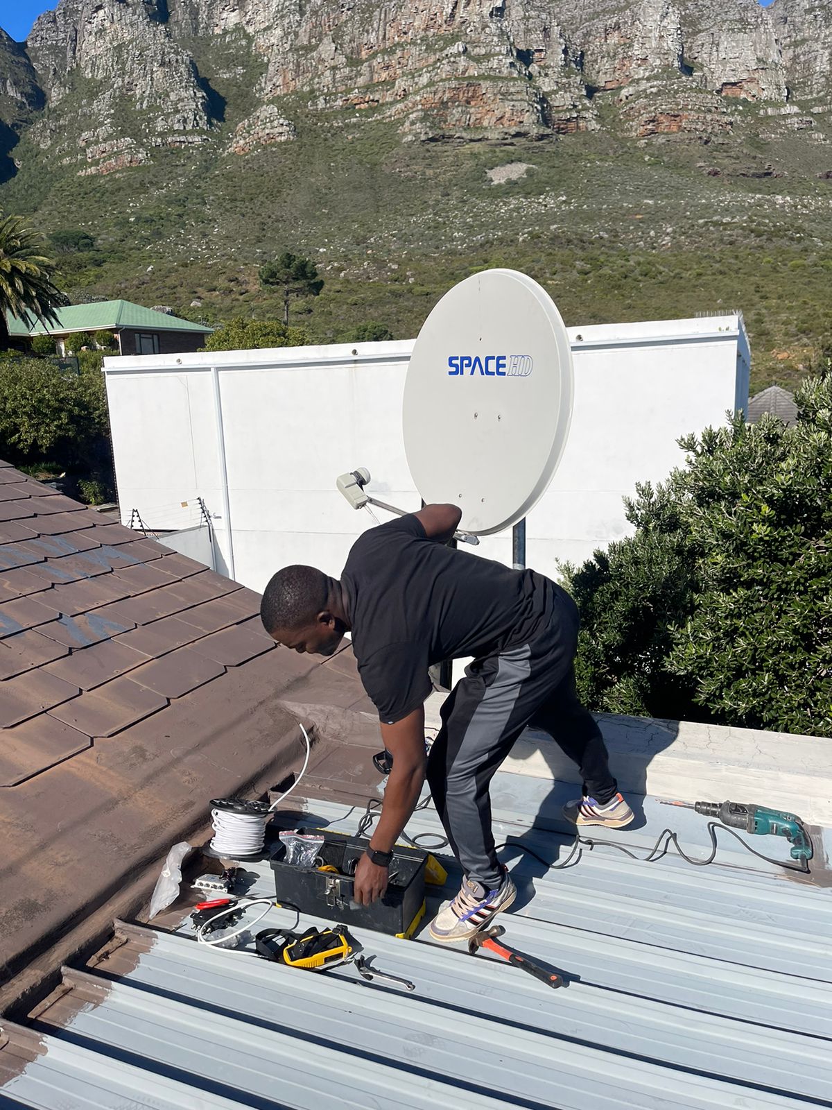 DStv technician installing and aligning a satellite dish on a roof